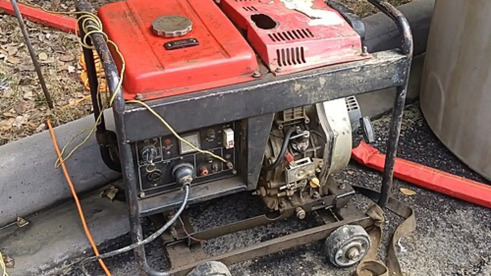 Groupe électrogène portable rouge en usage extérieur, câbles branchés